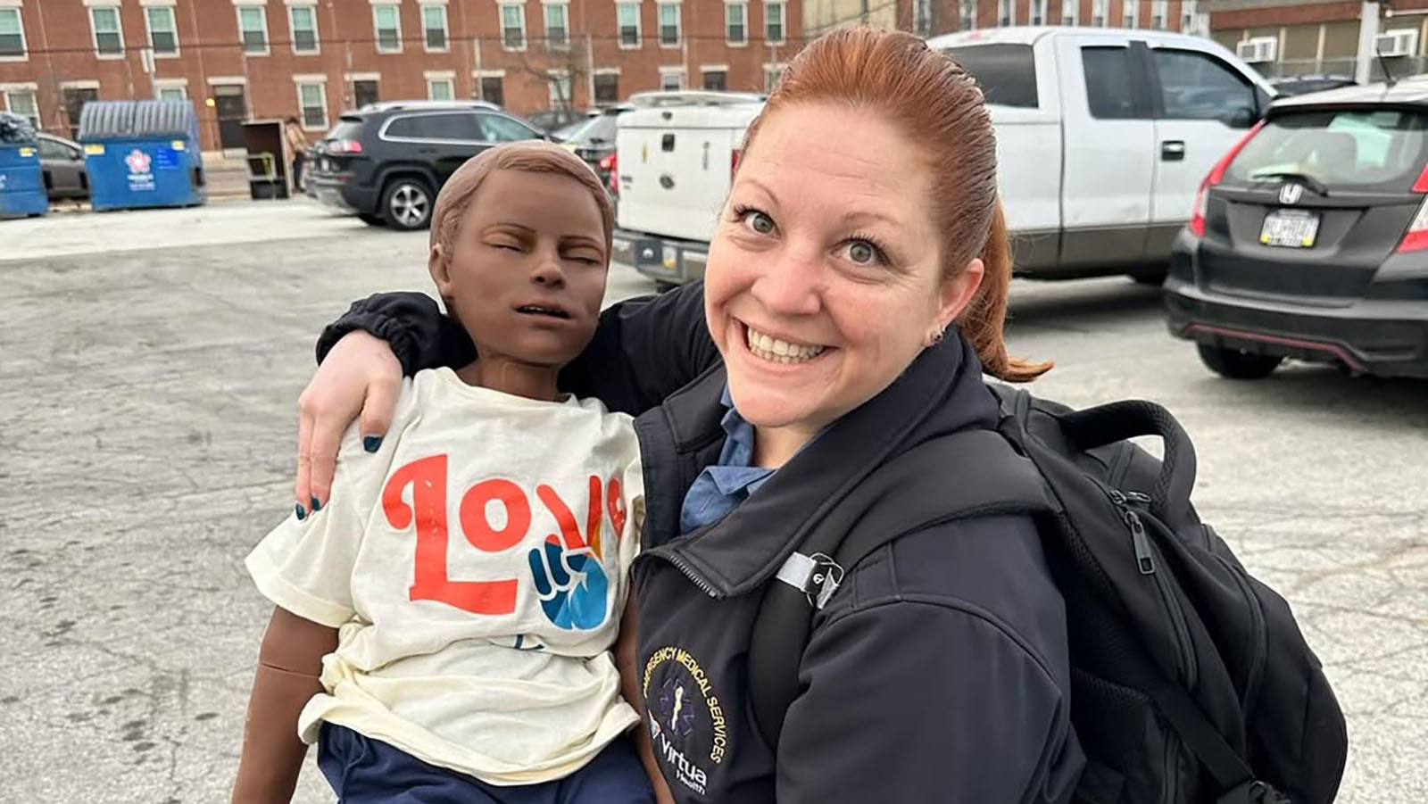 Instructor smiling and posing with CPR training dummy
