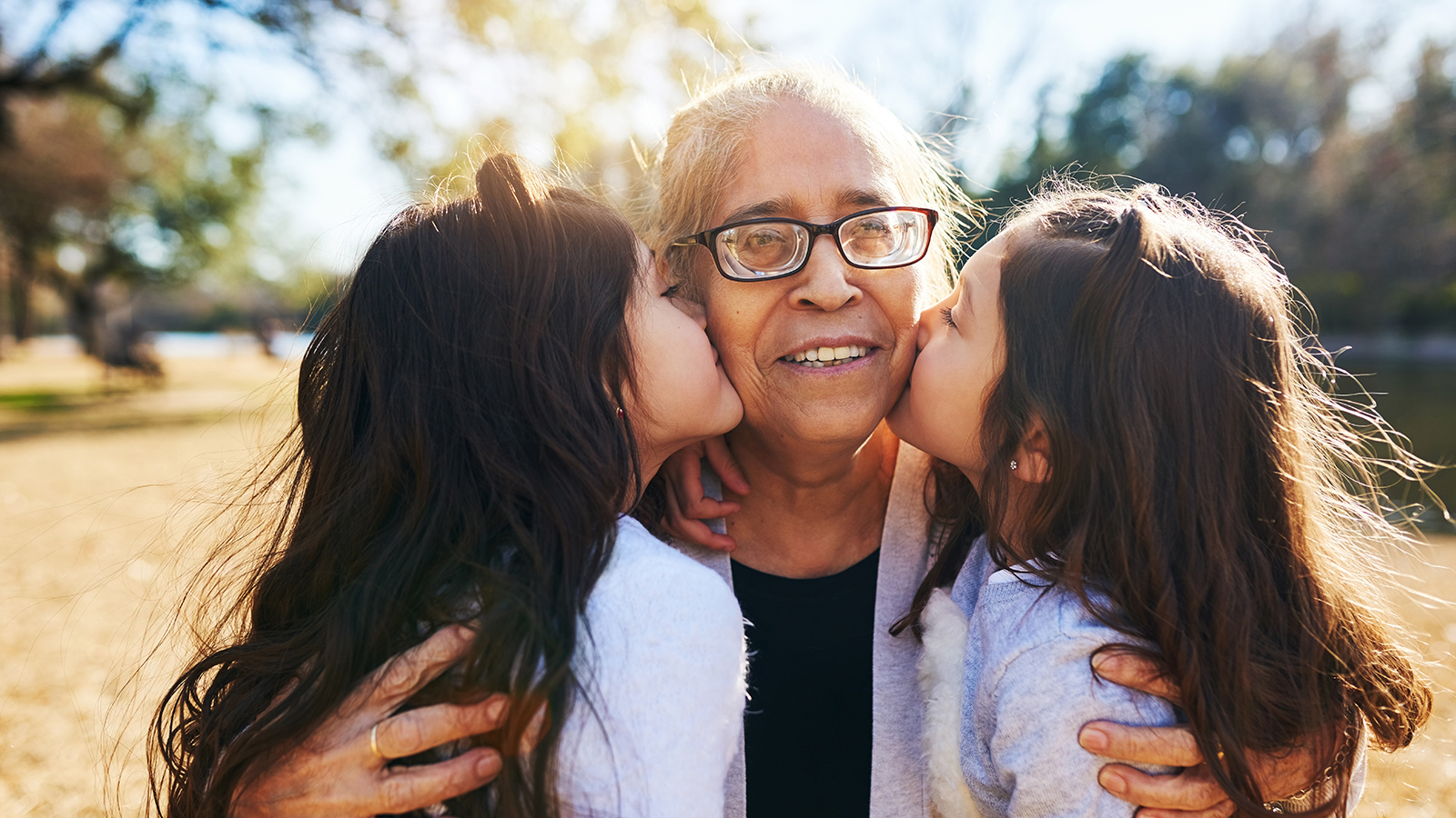 Elderly woman gets a kiss on each cheek from her granddaughters.