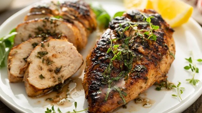 plated chicken breast and sliced chicken with lemon and herbs on the side