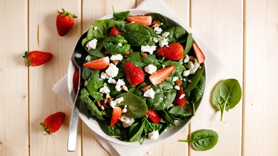 strawberry spinach salad in a bowl on a wooden tabletop