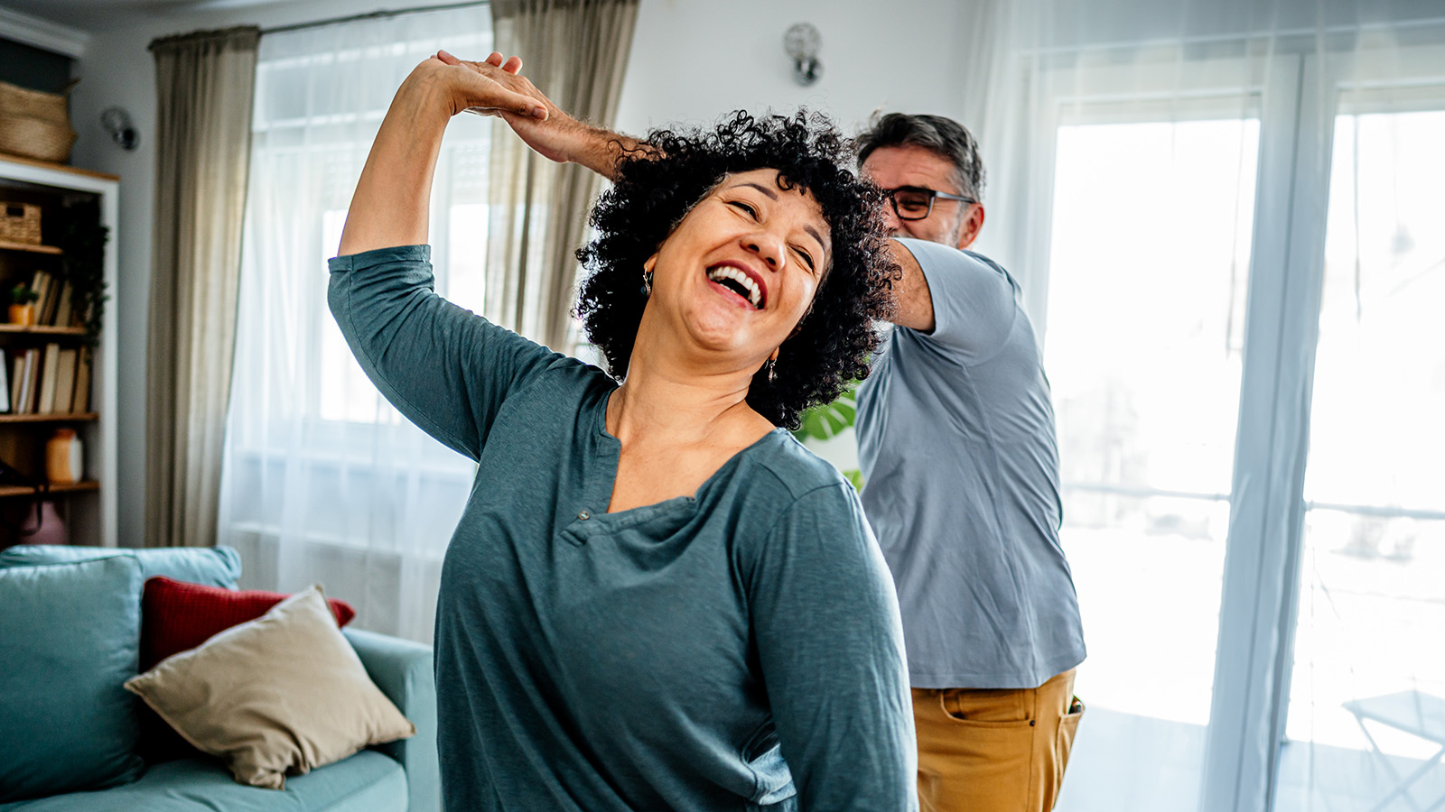 Middle-aged female dancing with her husband in their living room