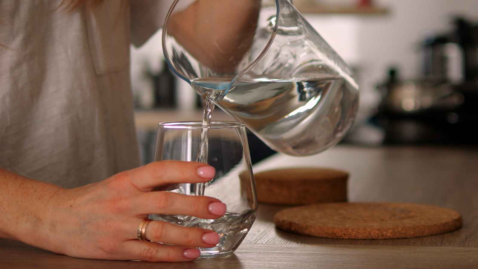 woman's hands pouring water from pitcher into glass