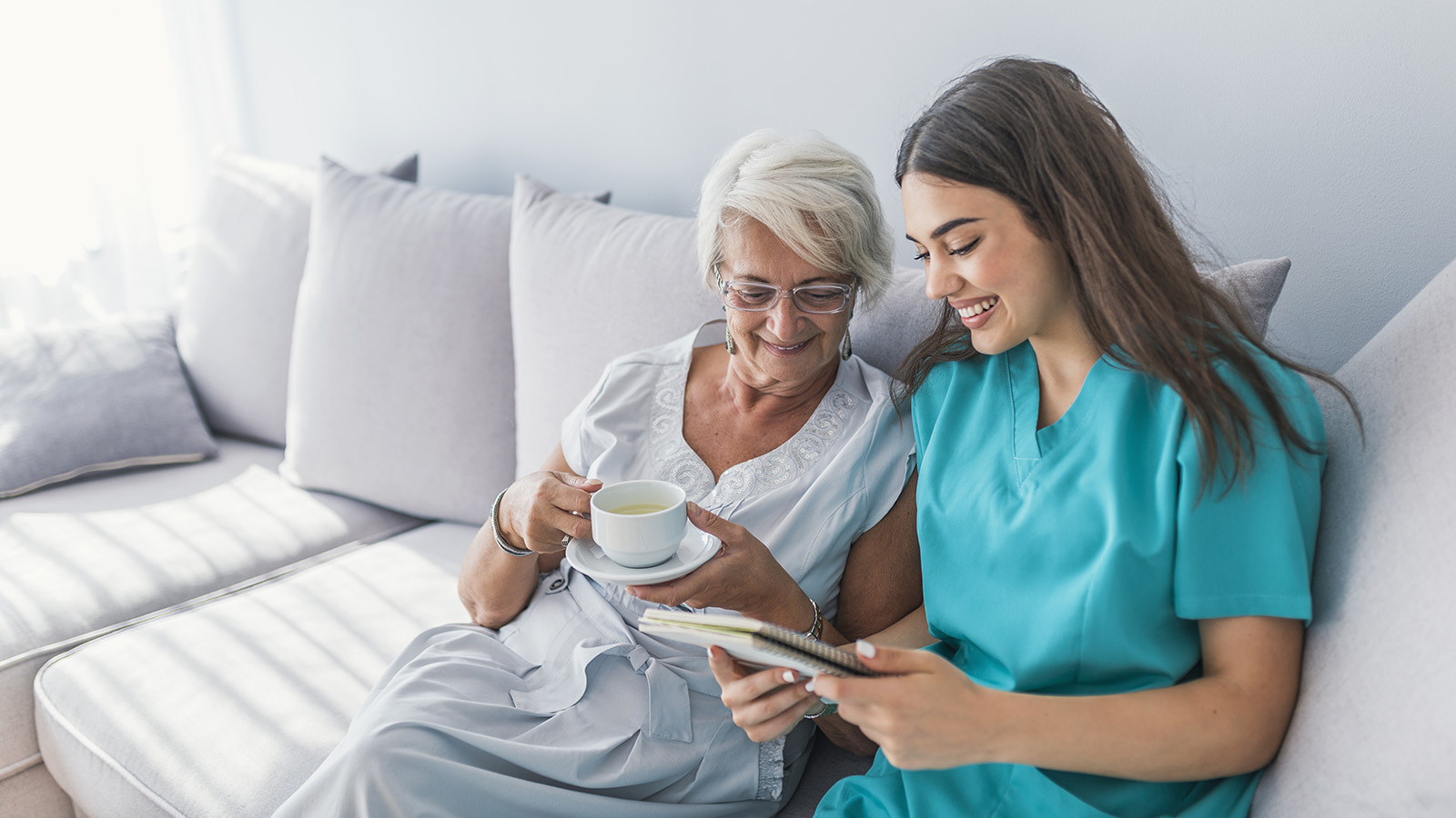 Older woman patient and caregiver spending time on the couch