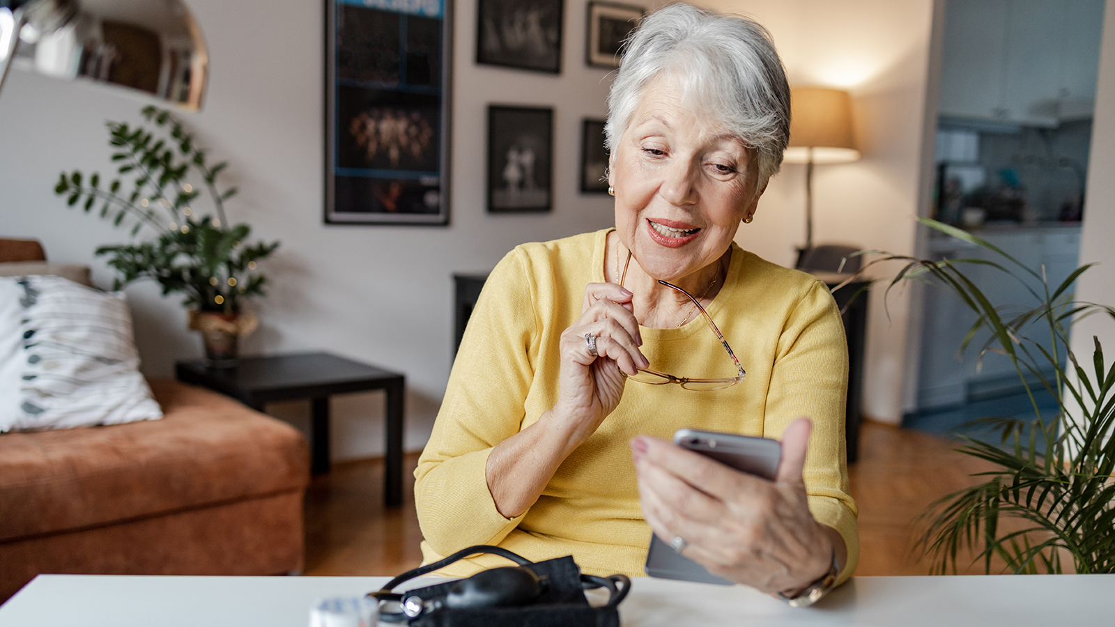 Elderly woman in a yellow shirt looks at her mobile phone