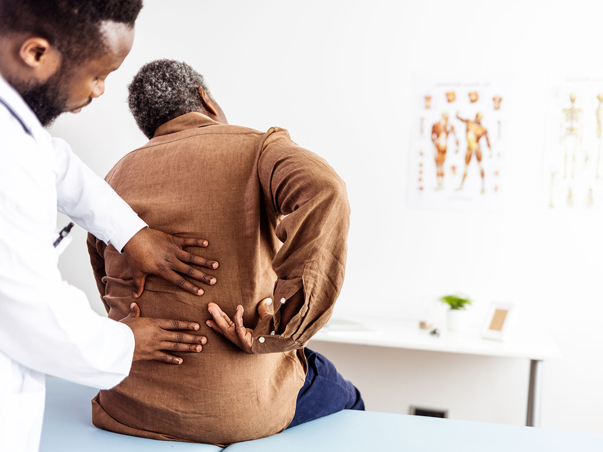Male doctor examining patient's back in clinic