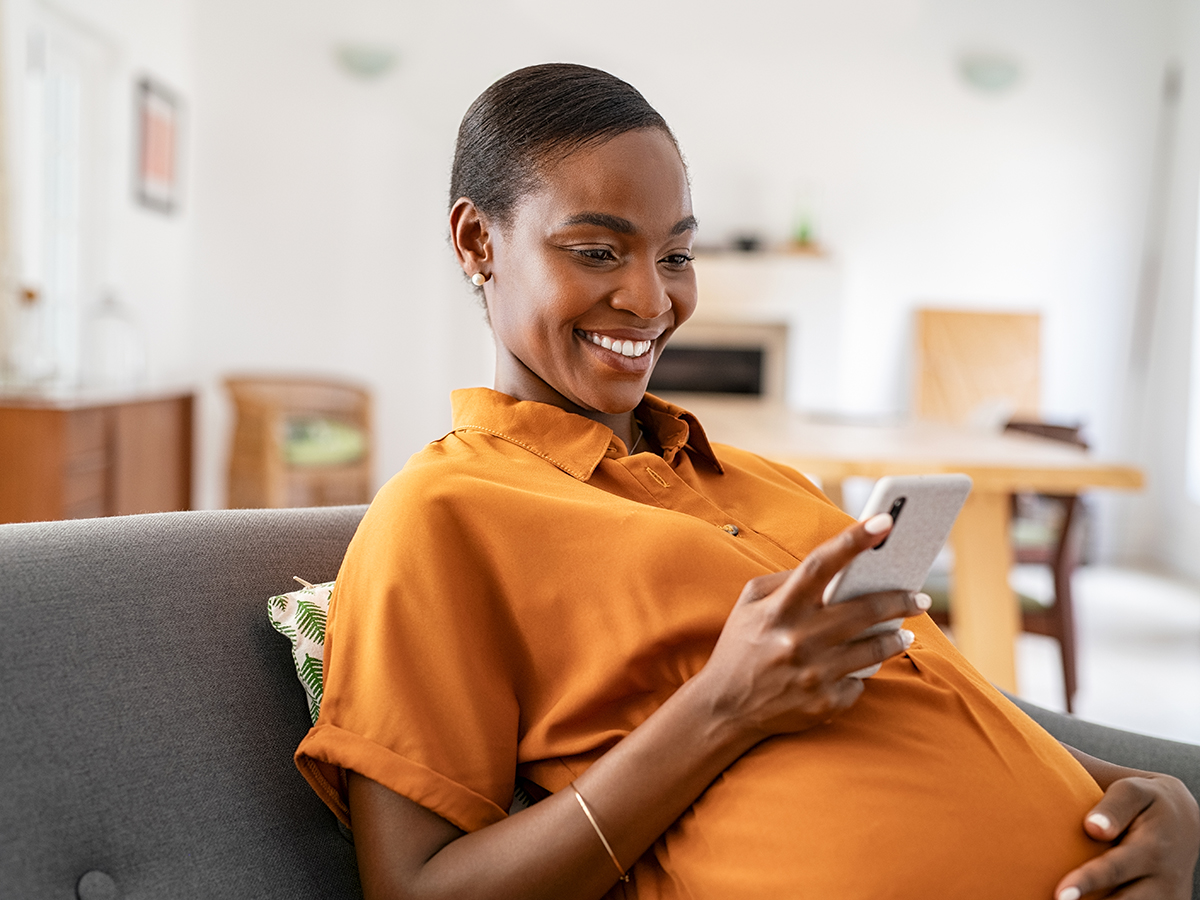 Pregnant woman smiles while checking her phone 